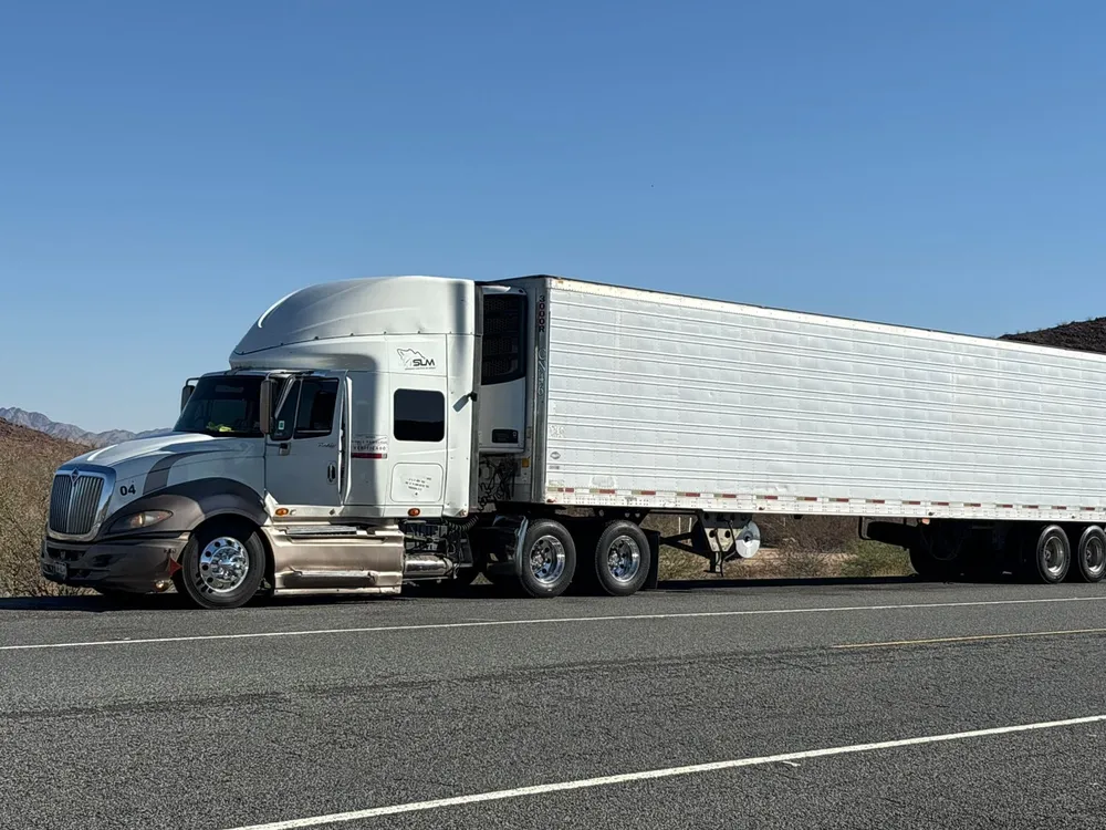 Tractocamion blanco de SLM con caja refrigerada en carretera